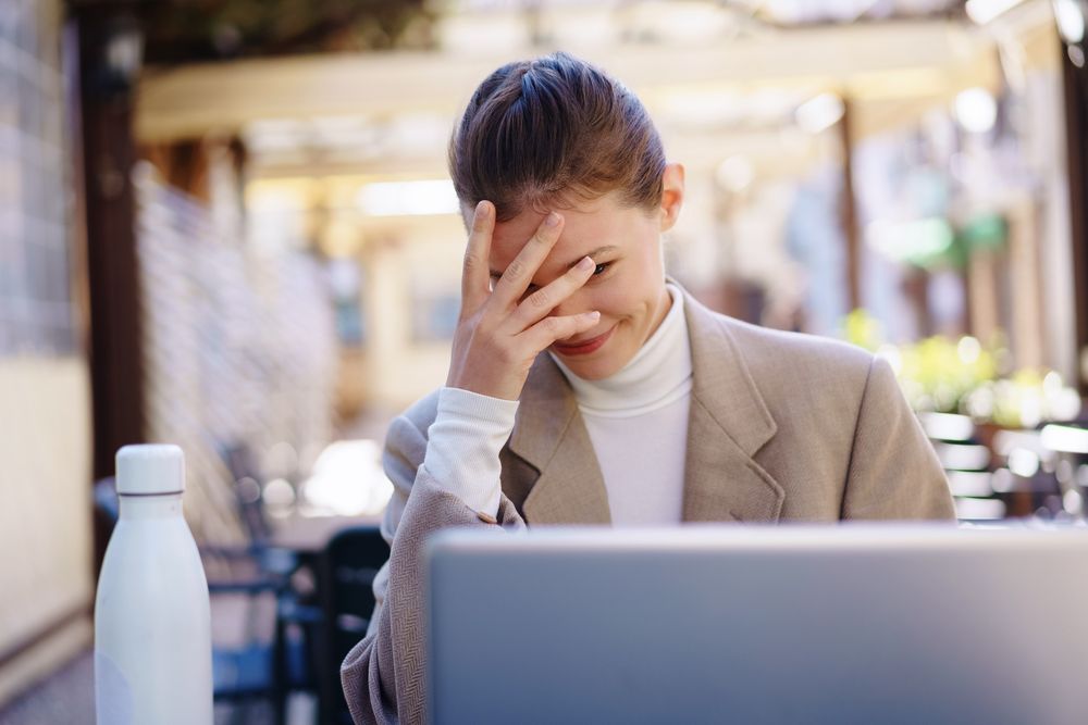 A frustrated professional is trying to work on a laptop outside, facing many distractions