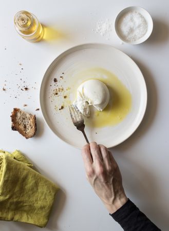 Crop hand taking cheese near bread and oil