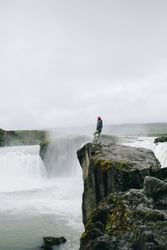 Man on cliff over waterfall, vertical