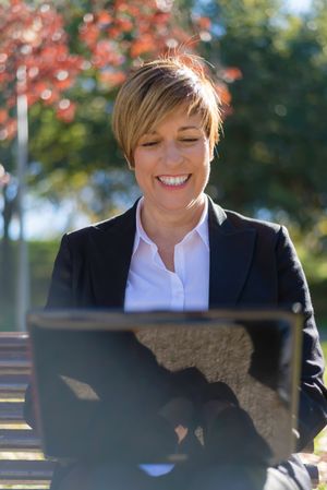 Smiling professional sitting in park with laptop