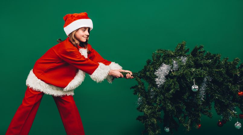 Girl dressed as Santa Claus taking down a Christmas tree