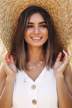Portrait of woman in beige top and straw hat on sunny day