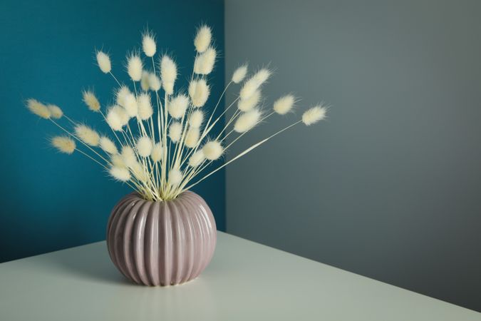 Round and ridged vase in blue and grey room filled with dried flowers with space for text