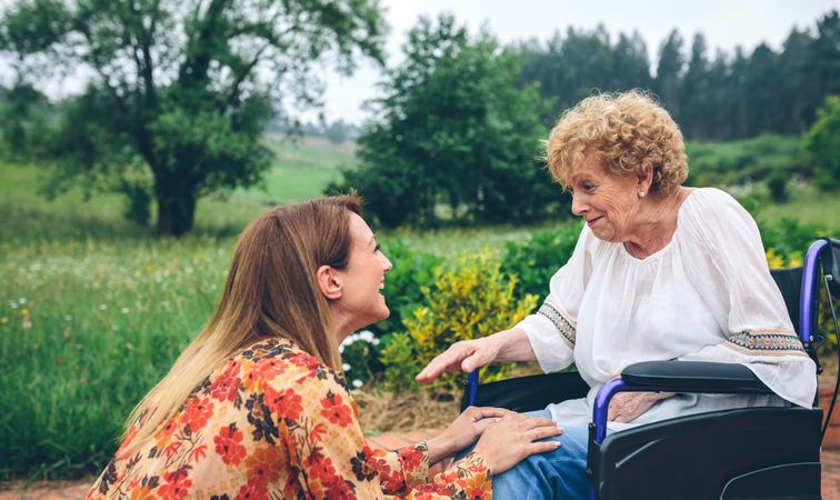 Young woman talking to mature relative in a wheelchair