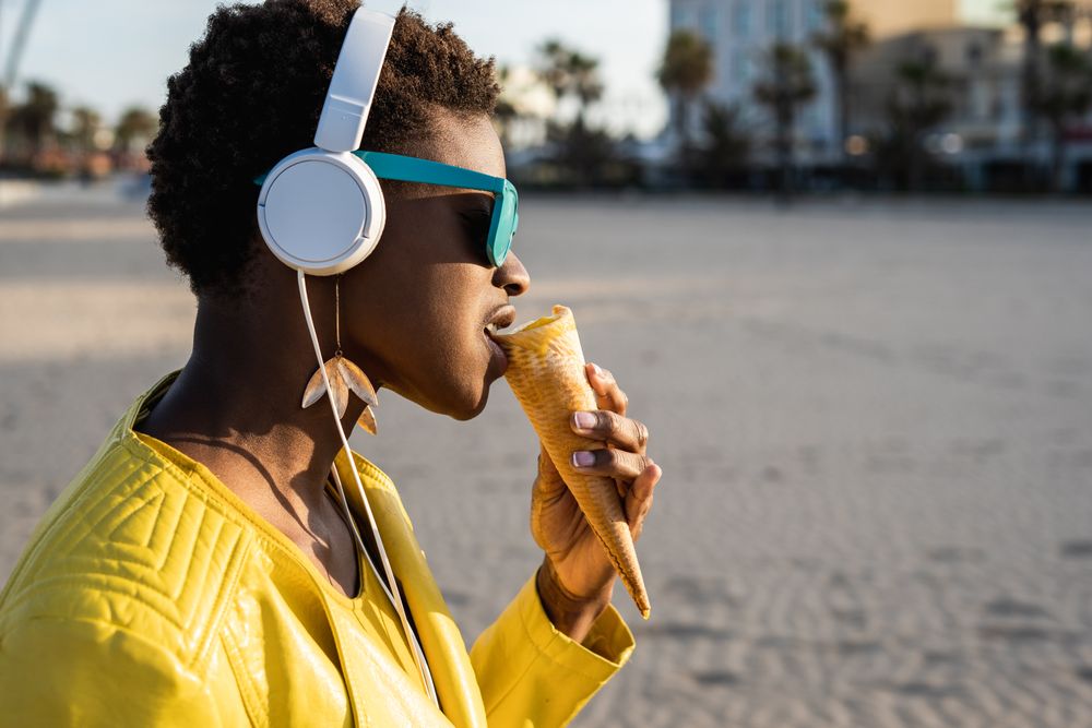 Cool female eating ice cream on beach