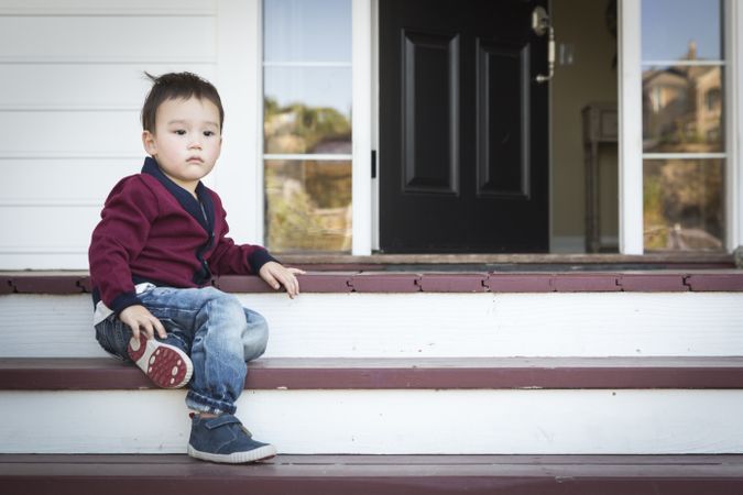 Melancholy Biracial Boy Sitting on Front Porch Steps