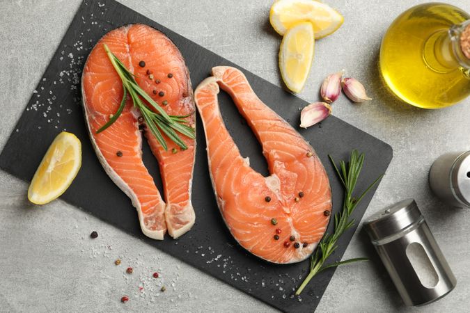 Composition with salmon meat and spices on gray background, top view