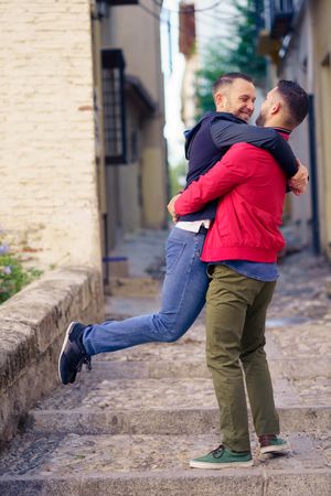 Male lifting up his partner in cute moment in narrow Spanish street
