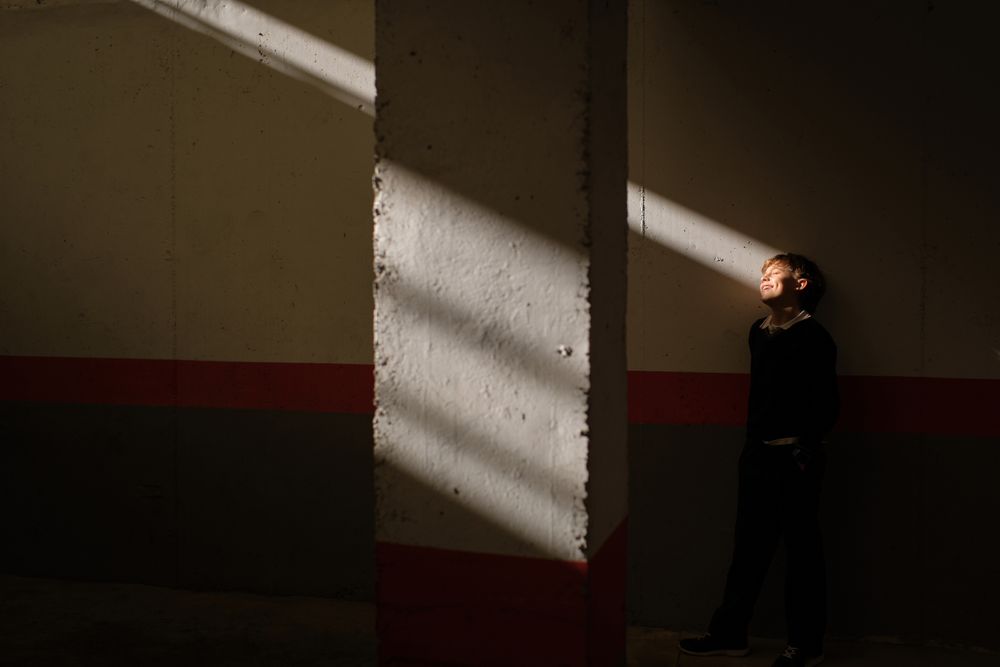 Adorable preteen boy standing near wall in sunbeam