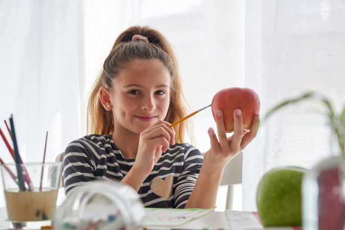 Positive girl painting on apple