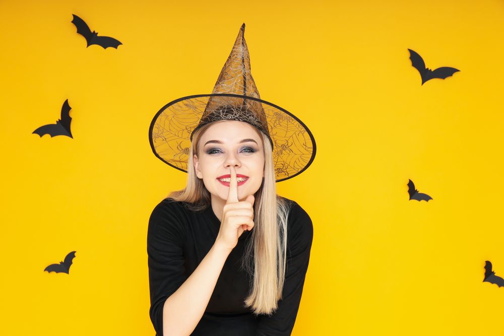 Concept of Halloween, young woman on yellow background