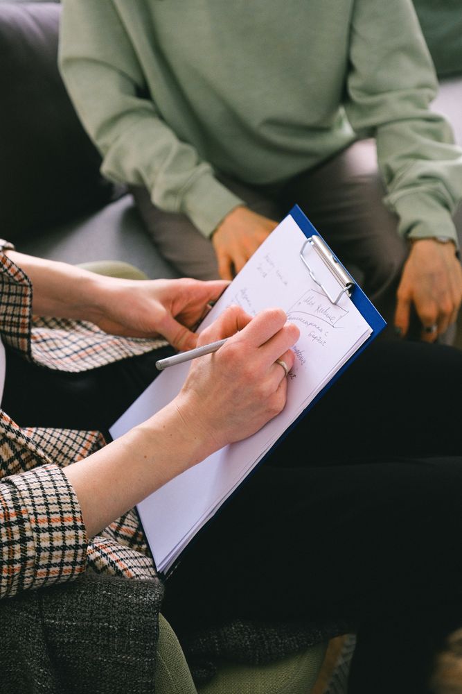 Cropped image of person writing a report sitting beside a person