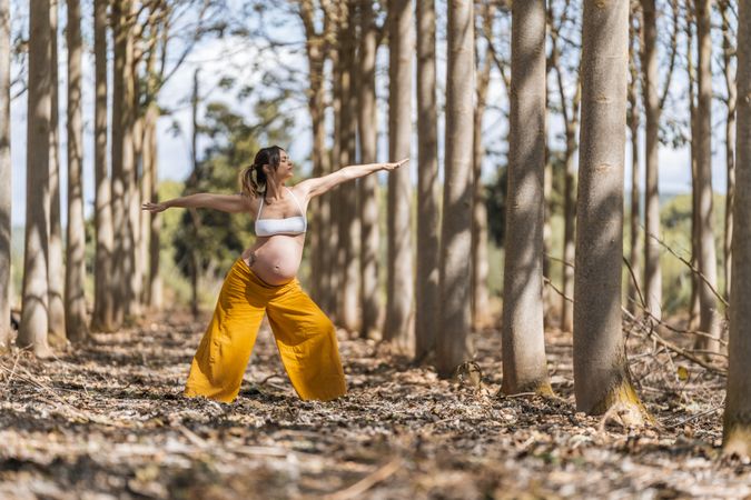 Concentrated adult expectant mother practicing yoga in park