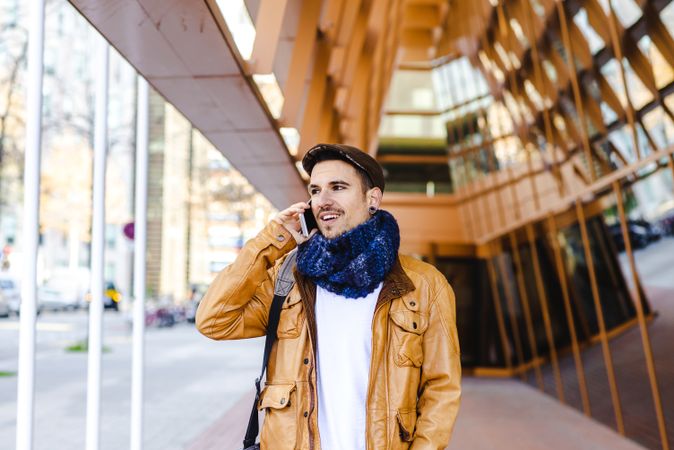 Stylish guy using smartphone outside modern building
