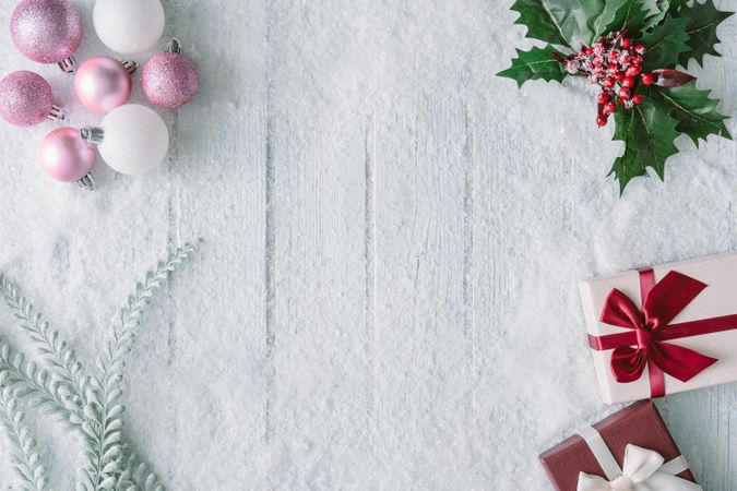 Wooden table background with snow and flowers and festive pink decorations, presents and gifts