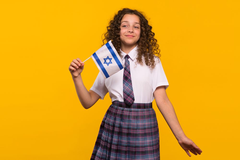 Girl waving Israeli flag with slight smile