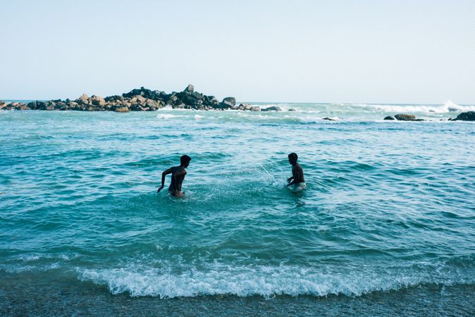 Two men splashing each other with water in Sri Lankan beach
