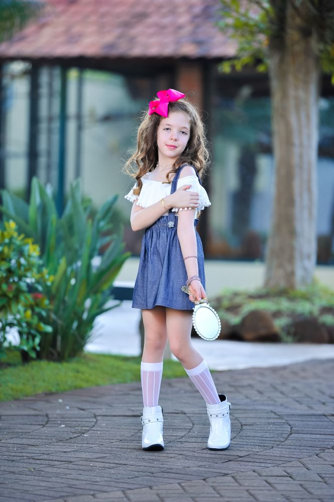 Girl standing holding mirror and touching her left bicep