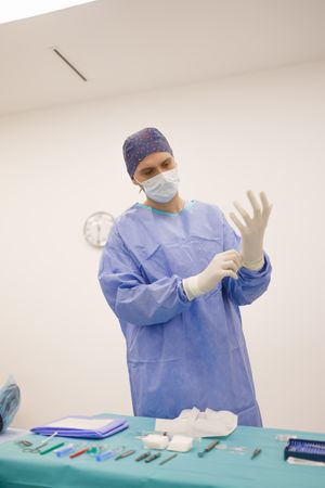 Surgeon putting on latex gloves, vertical