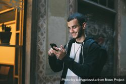 Man smiling while looking down at cell phone 4N7Prb