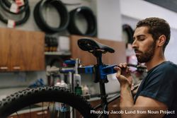 Worker with a beard concentrating on repairing a bicycle bYWzg5