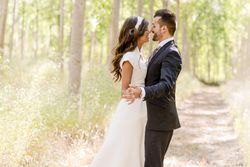 Newlyweds embracing for picture with poplar trees in background
