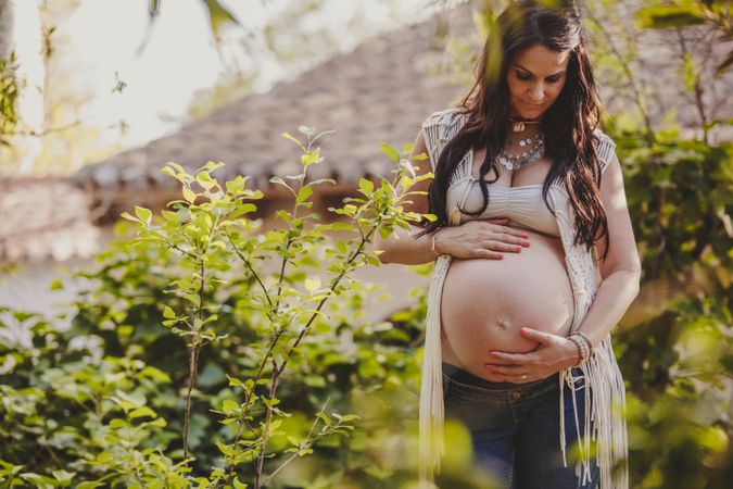 Pregnant woman touching belly in park