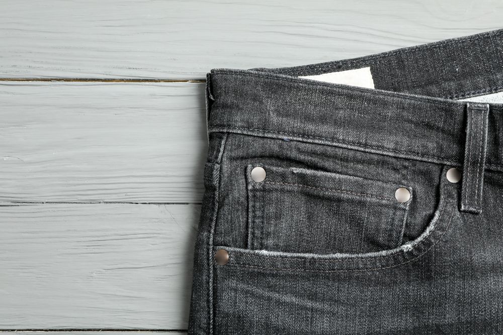 Jeans pocket on wooden background, space for text