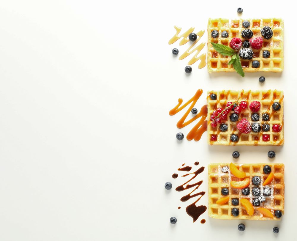 Flat lay composition with waffles and different toppings, top view