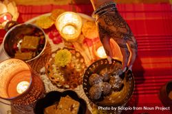 Top view of hand with mehndi beside Diwali's desserts and candles 0P9125
