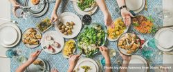 Group of people at blue patterned table with fresh fruits, salad, and vegetables, wide composition 42np14