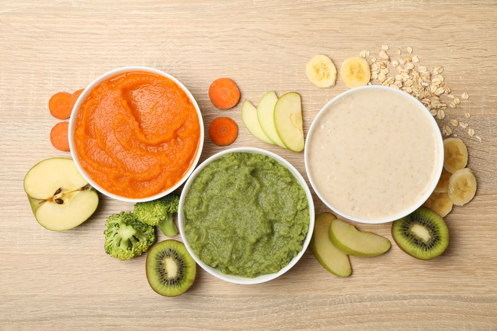 Bowls with vegetable puree on wooden background. Baby food
