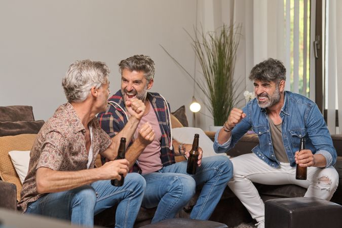 Men drinking beer and celebrating victory at home
