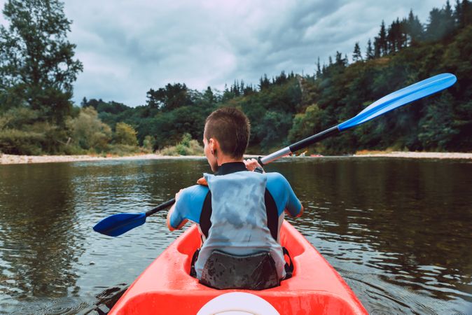Female kayaking with paddle in raised hands