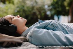 Side view of a woman relaxing outdoors listening to music wearing headphones 4OnAR5