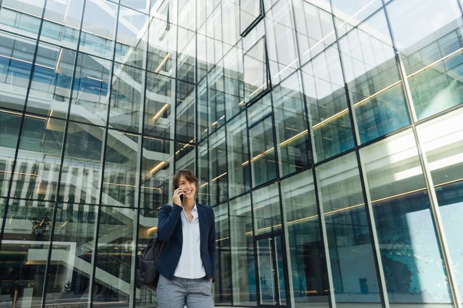 Smiling entrepreneur browsing smartphone outside office building