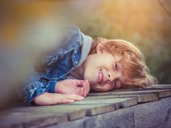 Cheerful kid lying on boardwalk