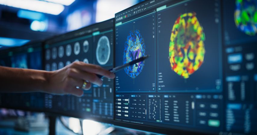 Modern Medical Research Center: Anonymous Doctor Pointing At Desktop Computer Monitor With CT Scan Of Patient's Spinal Cord.