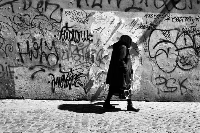 Side view of woman walking past graffiti