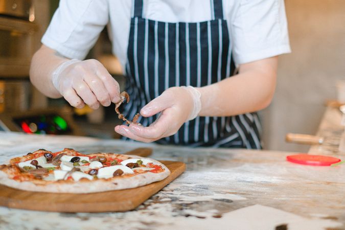 Cropped image of chef adding pizza topping