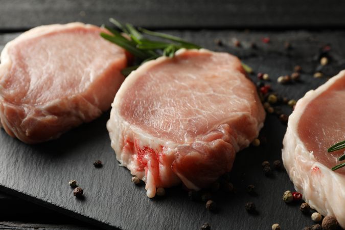 Composition with raw meat for steak and spices on wooden background