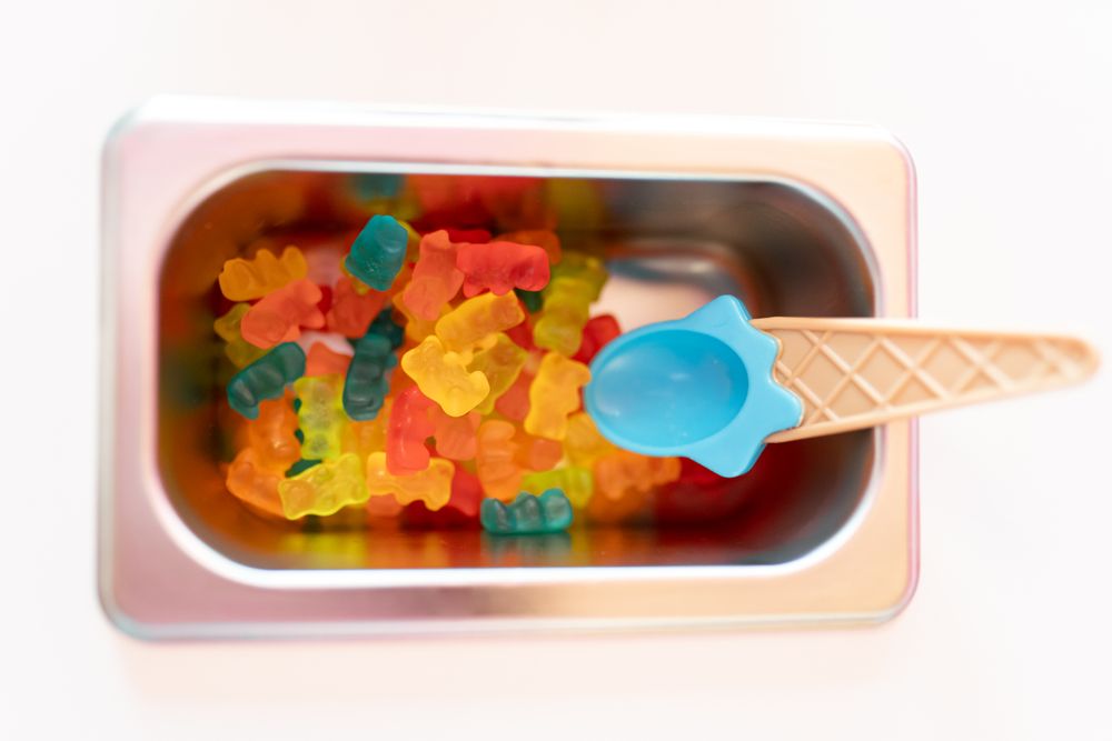 Close up photo of a metal tray filled with teddy bear gummy toppings on an ice cream parlor counter