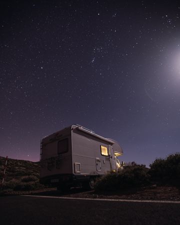 Caravan on roadside under night starry sky