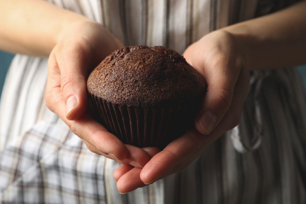Woman holds tasty chocolate muffin, close up