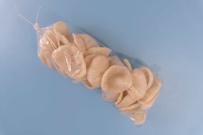A sealed plastic bag of traditional crackers (kerupuk) tied at the top. Ideal for food packaging mockups, local snack promotions, or culinary blog illustrations...