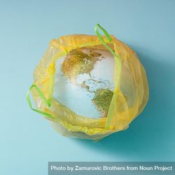 Earth in plastic yellow trash bag on blue background 0La3R5