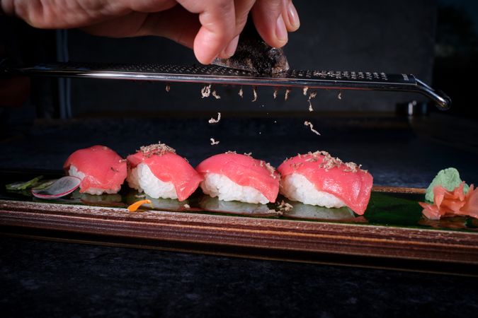 Crop chef decorating sushi with truffle