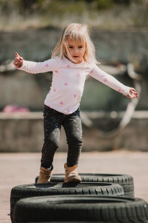 Cute girl walking on car tires