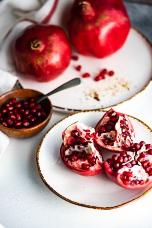 Fresh cut pomegranate on light plate with bowl of seeds