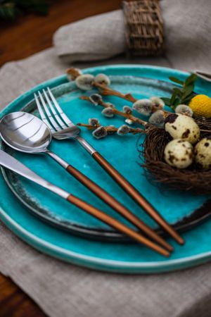 Easter table setting with delicate bird nest on teal plate